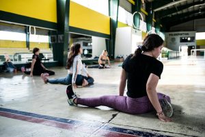 Women engaging in a group stretching session in an indoor gym.