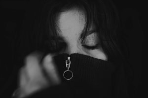 Black and white close-up of a woman with eyes closed, wearing a sweater.