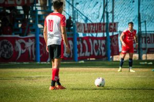 Soccer players on the field in Mendoza, Argentina, prepared for a competitive match under bright sunlight.