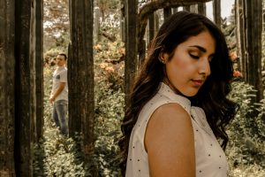 A man and woman in a forest exhibit emotions of love and separation.