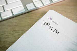 Close-up of a to-do list next to a computer keyboard on a desk.