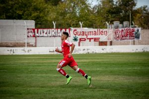 Dynamic shot of a young soccer player running on a football field during a match.