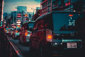 Bustling city traffic during twilight with vibrant lights and modern architecture.