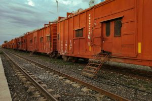 A line of vintage train wagons on railway tracks in El Fuerte, Mexico, under overcast skies.