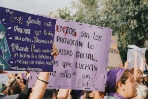 Women holding protest signs during a social justice demonstration outdoors.