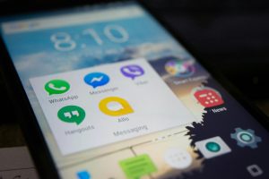 Smartphone screen showing various messaging apps like WhatsApp and Messenger.