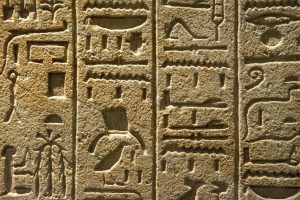 Close-up of ancient Egyptian hieroglyphs carved into a stone wall, showcasing cultural history.