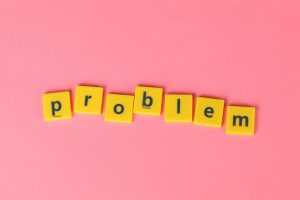 Yellow tiles spell 'problem' on a vibrant pink background, conveying creativity and wordplay.