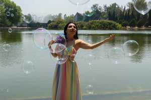 Woman enjoying a sunny day by the lake with bubbles around her in Mexico City.