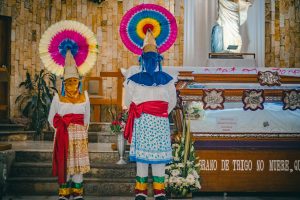 Colorful traditional ceremony featuring cultural masks and outfits in Huauchinango, Mexico.