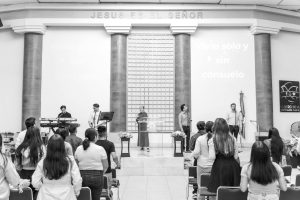A black and white photo capturing a church concert in Mexico with people standing and worshiping.