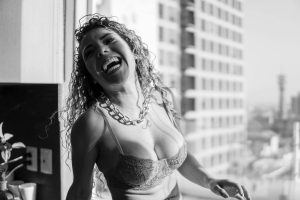 Black and white portrait of a smiling woman with curly hair and a necklace, exuding joy in Mexico City.