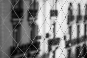 Monochrome photo of wire fence with blurred urban architecture in Buenos Aires.