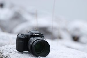 A Canon EOS camera rests on a snow-covered surface in Jönköping, Sweden, during winter.