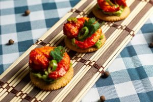 Tasty shrimp appetizers with guacamole and jalapeños served on crackers.