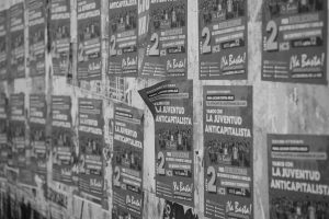 Street covered with political posters promoting anti-capitalist youth movements in Córdoba.