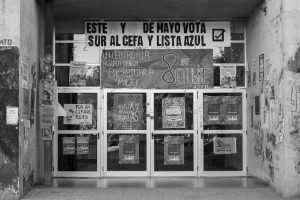 Black and white photo of an entrance covered with political posters in Córdoba, Argentina.