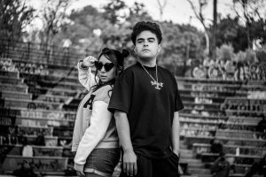 Edgy black and white portrait of two adults in a graffiti-covered urban setting.