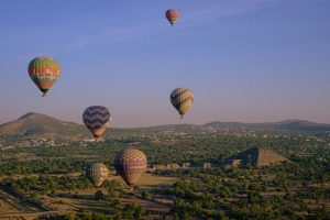 Colorful hot air balloons soaring over the ancient pyramids of Teotihuacan, Mexico.