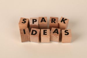 Creative composition of wooden letter blocks forming the phrase 'Spark Ideas' on a neutral background.