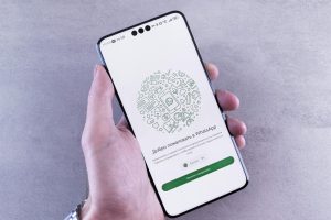 Close-up of a hand holding a smartphone displaying the WhatsApp welcome screen in Russian.