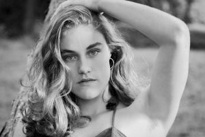 Elegant black and white portrait of a young woman in a natural setting.