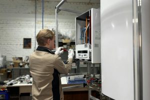 Technician inspects and repairs a heating system in an industrial workshop setting.