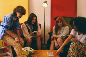 Four adults engaging in a tarot card reading session in a cozy, colorful room.