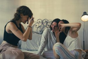 Three young women having fun at a cozy sleepover, capturing joyful moments.
