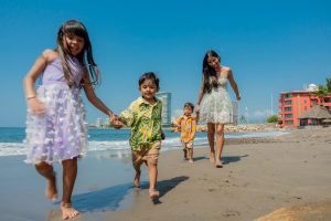 Cheerful family playing and running on a sunny beach, enjoying a vacation day together.