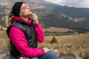A woman in vibrant pink attire enjoys the serene mountain view in Puebla, Mexico.