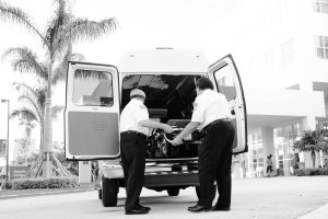 Black and white photo of emergency responders loading equipment into an ambulance outside a medical building.