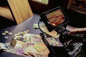 Camera setup capturing various global currencies on a table, detailed professional shot.
