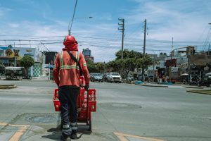 A city worker with a handcart on a bustling street in Trujillo, Peru under a bright blue sky.