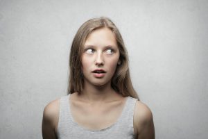 Young woman looking sideways with a curious expression in a studio portrait.