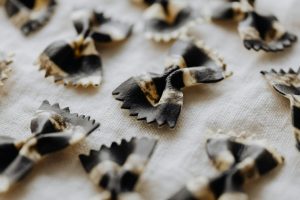 Detailed view of uncooked striped bowtie pasta arranged on a white cloth surface.