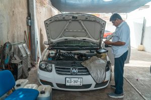 A mechanic examines a Volkswagen engine in a garage setting, focusing on car maintenance.