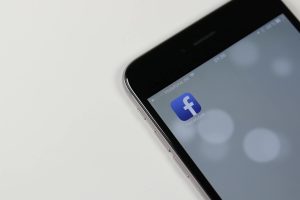 iPhone displaying Facebook app icon with blurred background, emphasizing social media connectivity.