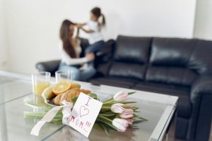 Tulips and a heartfelt note on a table with a mother and child in the background.