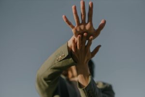 A person in artistic hand gestures reaching towards the sky, emphasizing expression and motion.