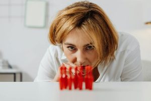 A woman intently observing red game pieces on a table, with selective focus highlighting concentration.