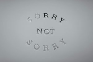 Minimalist design featuring the phrase 'Sorry Not Sorry' arranged in a circular pattern on a white background.