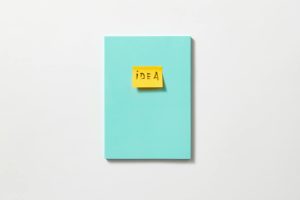 Yellow sticky note with 'idea' on a teal book, symbolizing creativity and inspiration.