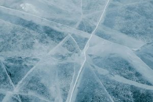 A detailed view of cracked ice on a frozen lake during winter, showcasing natural textures.