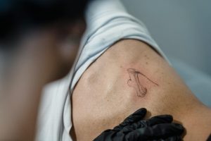 Close-up of a tattoo artist working on an abstract design on a person's back.