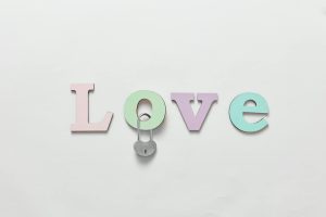 Palabras que enloquecerán a cualquier hombre Colorful pastel letters spelling 'Love' with a padlock, minimal design on a white background.