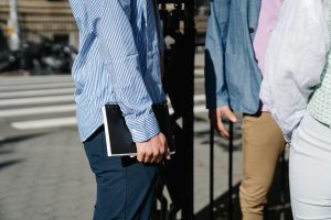 Group of casually dressed people standing outdoors with notebooks in the city.