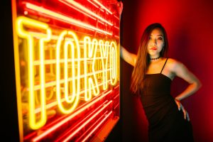 A stylish woman poses by a vibrant Tokyo neon sign, exuding modern urban nightlife.