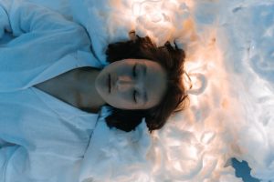 Tranquil portrait of a woman lying peacefully on cloud-like surroundings, evoking calmness.