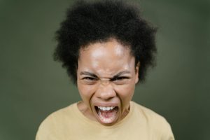 Close-up of an African American woman with afro hair expressing anger in a studio setting.